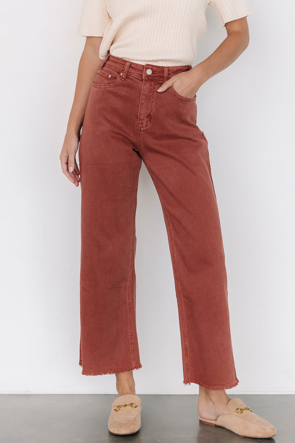 Front view of Spence terracotta high-rise denim pants on model, showing straight leg, unfinished hem, and front pockets for styling.