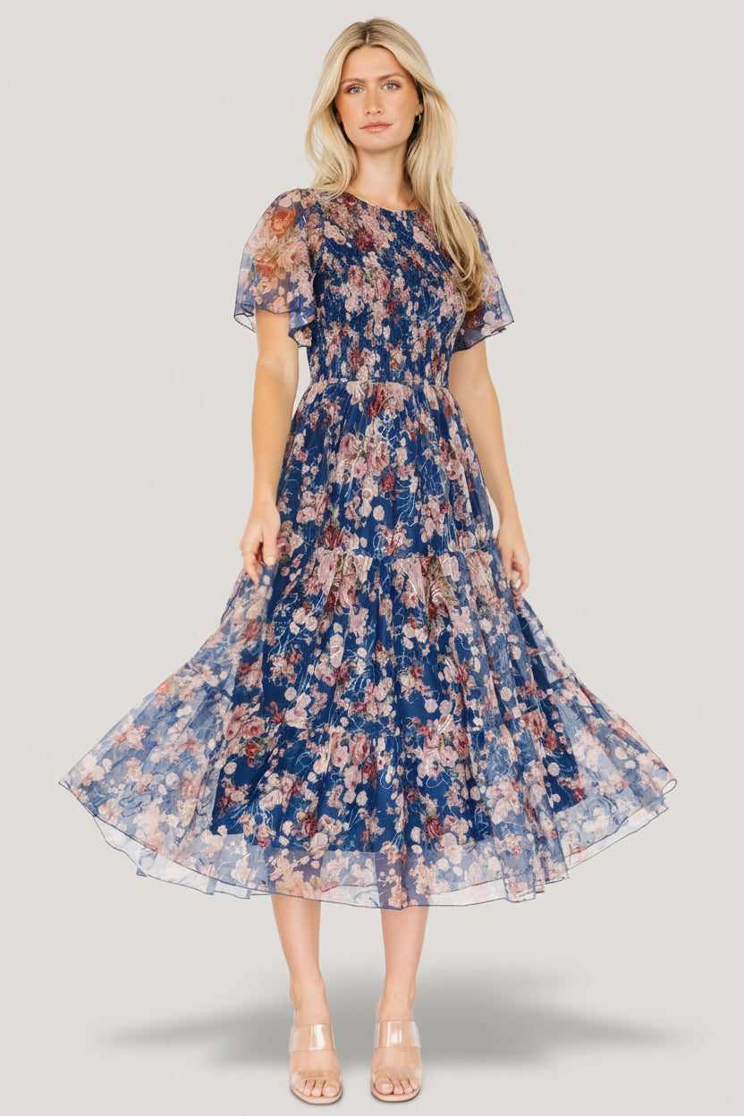 Full-length studio shot of the tiered midi skirt in motion showing the flowing tulle tiers, embroidered floral pattern, and soft drape.