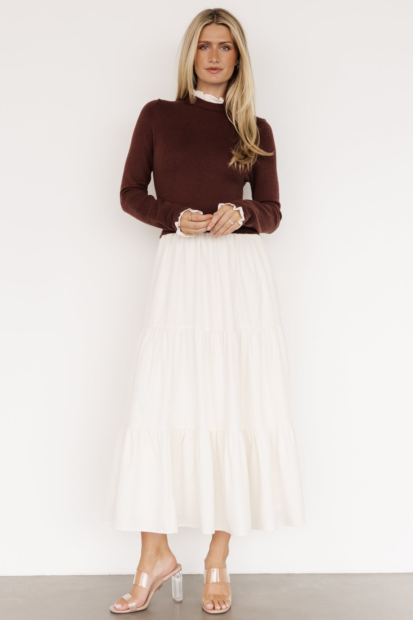 Three-quarter view of the Sophie Sweater Dress in mahogany and ivory, highlighting the flowing three-tier skirt and hidden side pocket detail.