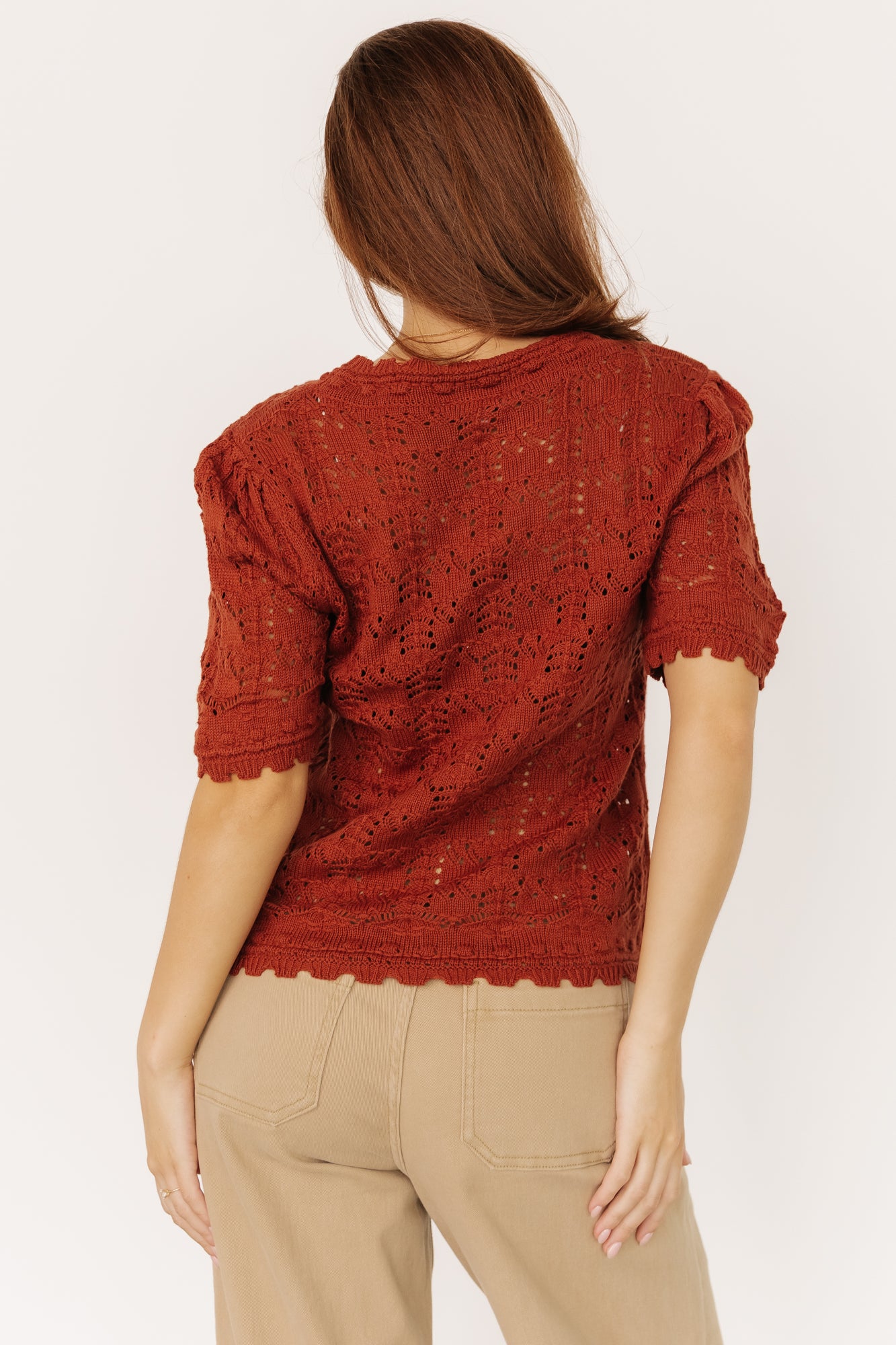 Styled flat-lay of Serenity Knit Sweater Top in rust paired with high-waist denim to show cropped length and scalloped hem detail.