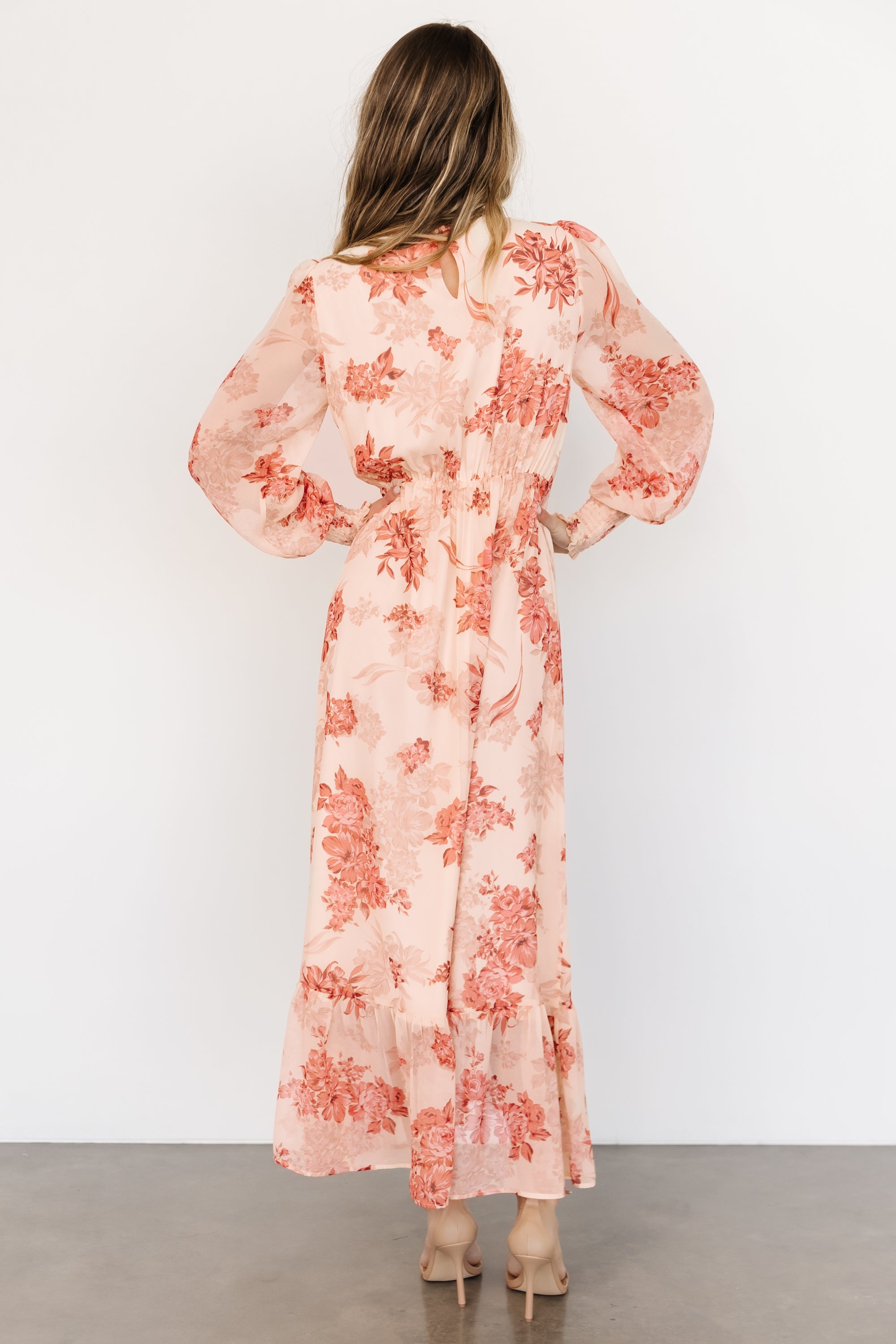 Styled shot of Luciana maxi dress paired with neutral accessories, showing versatile beige and rose floral print suitable for wedding guests.