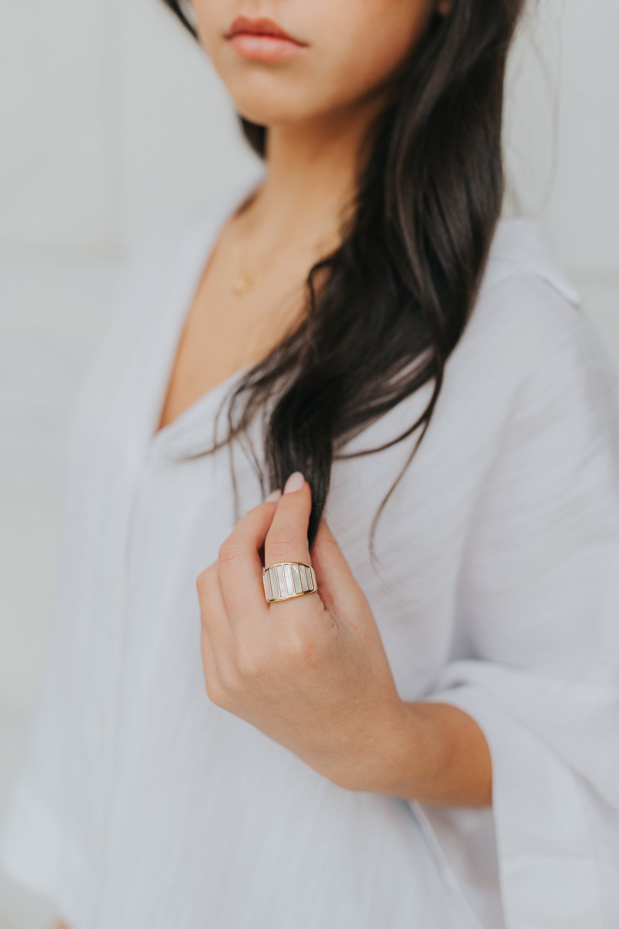 Close-up of the ring's inlay and band edge showing the mother-of-pearl panels set into the wide gold-tone band and smooth interior finish.