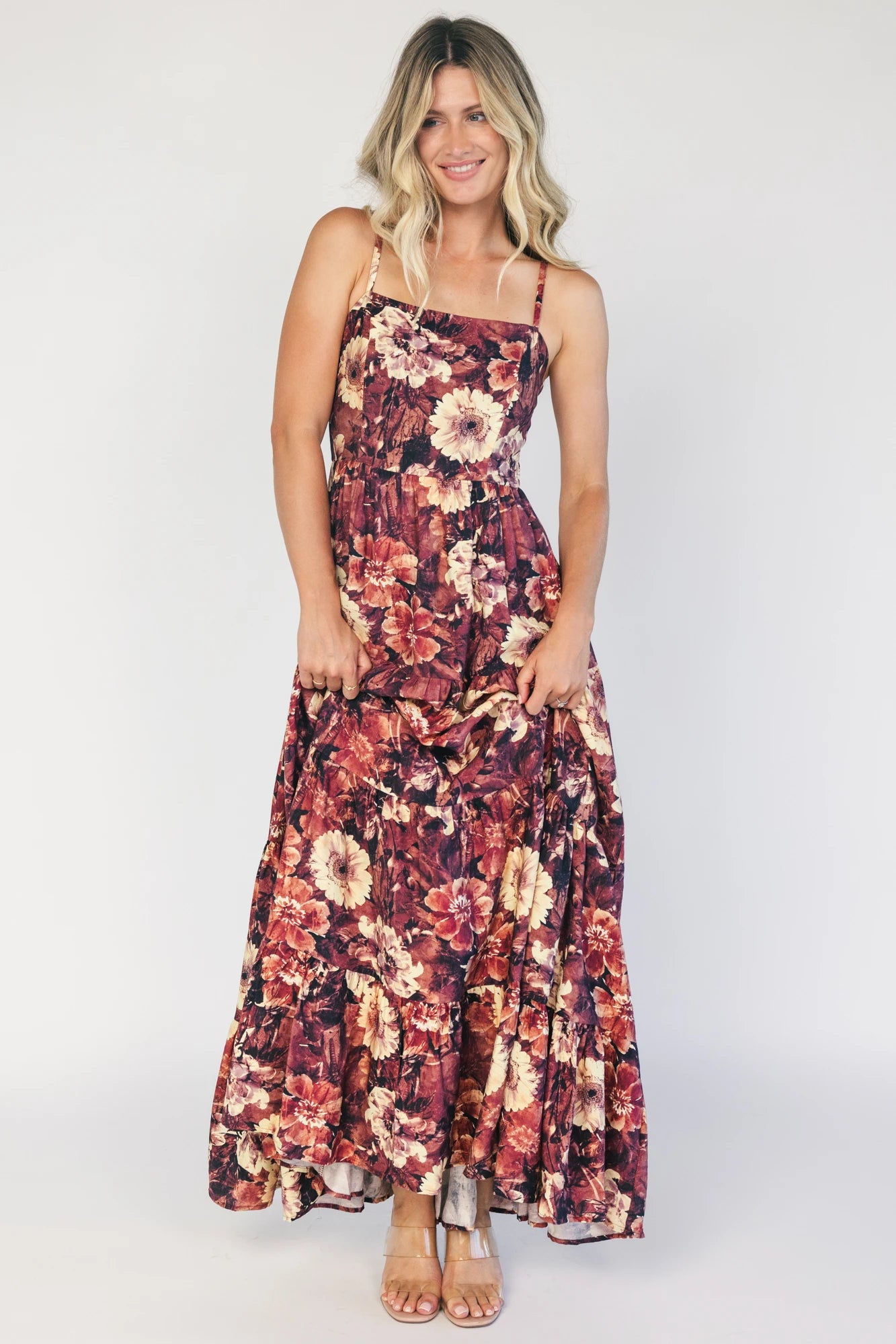 Model wearing a deep berry floral maxi dress with a square neckline, adjustable spaghetti straps, and a smocked back bodice.
