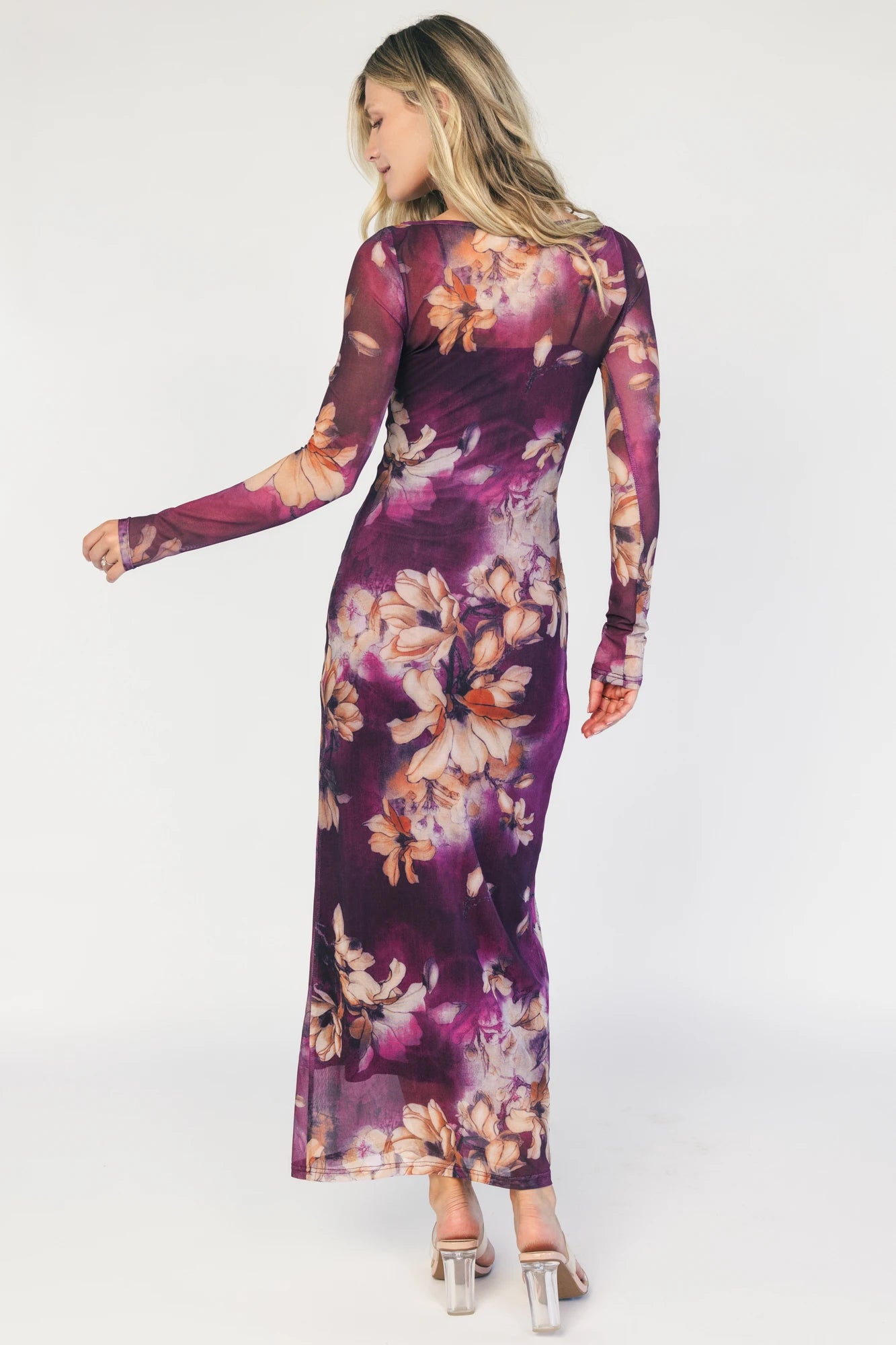 Model wearing a purple floral mesh midi dress with a round neckline, long sheer sleeves, and a fitted bodycon silhouette.