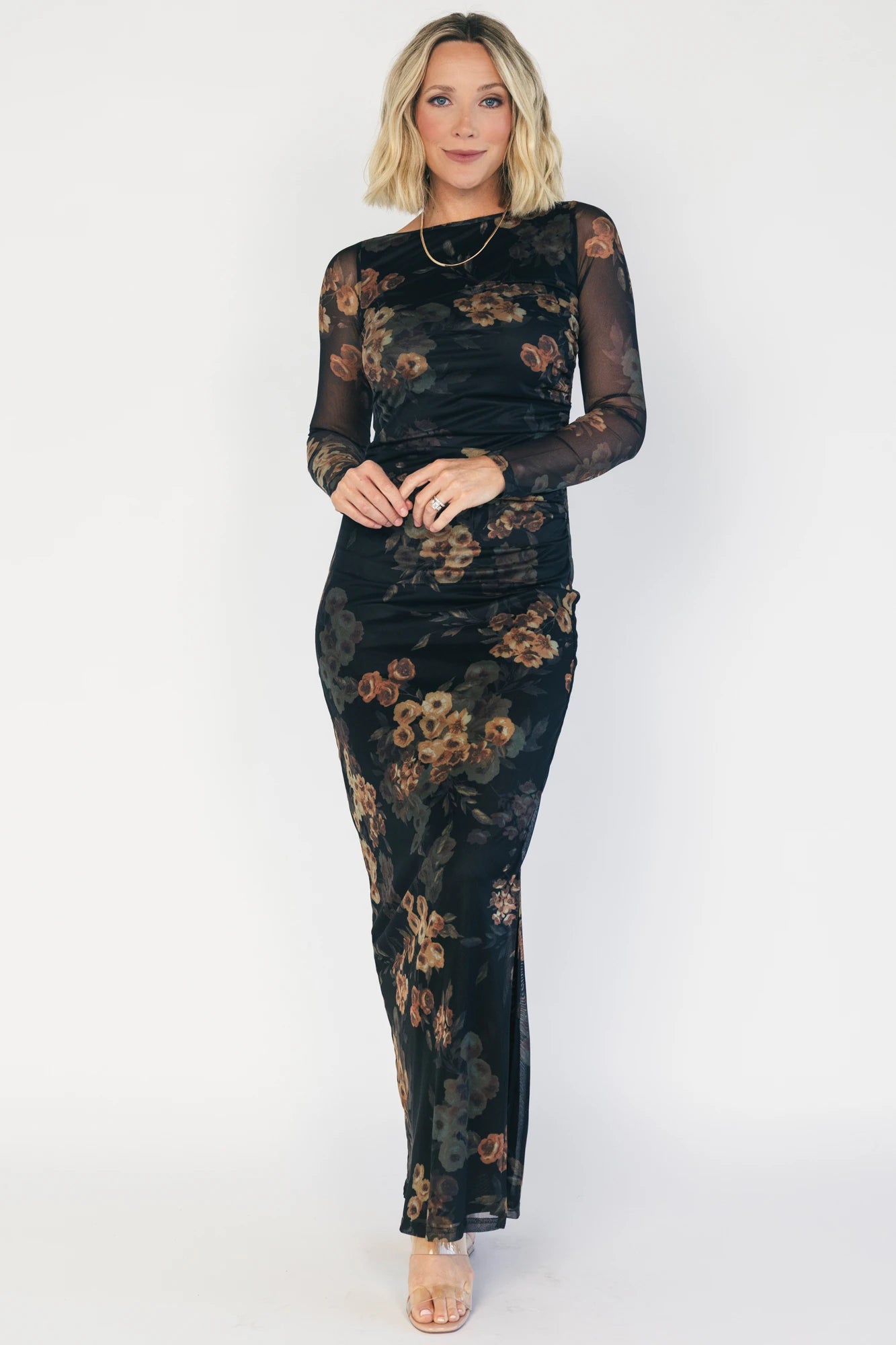Black mesh bodycon midi dress with muted gold floral print, sheer long sleeves, a round neckline, flattering side ruching, and a thigh-high side slit.