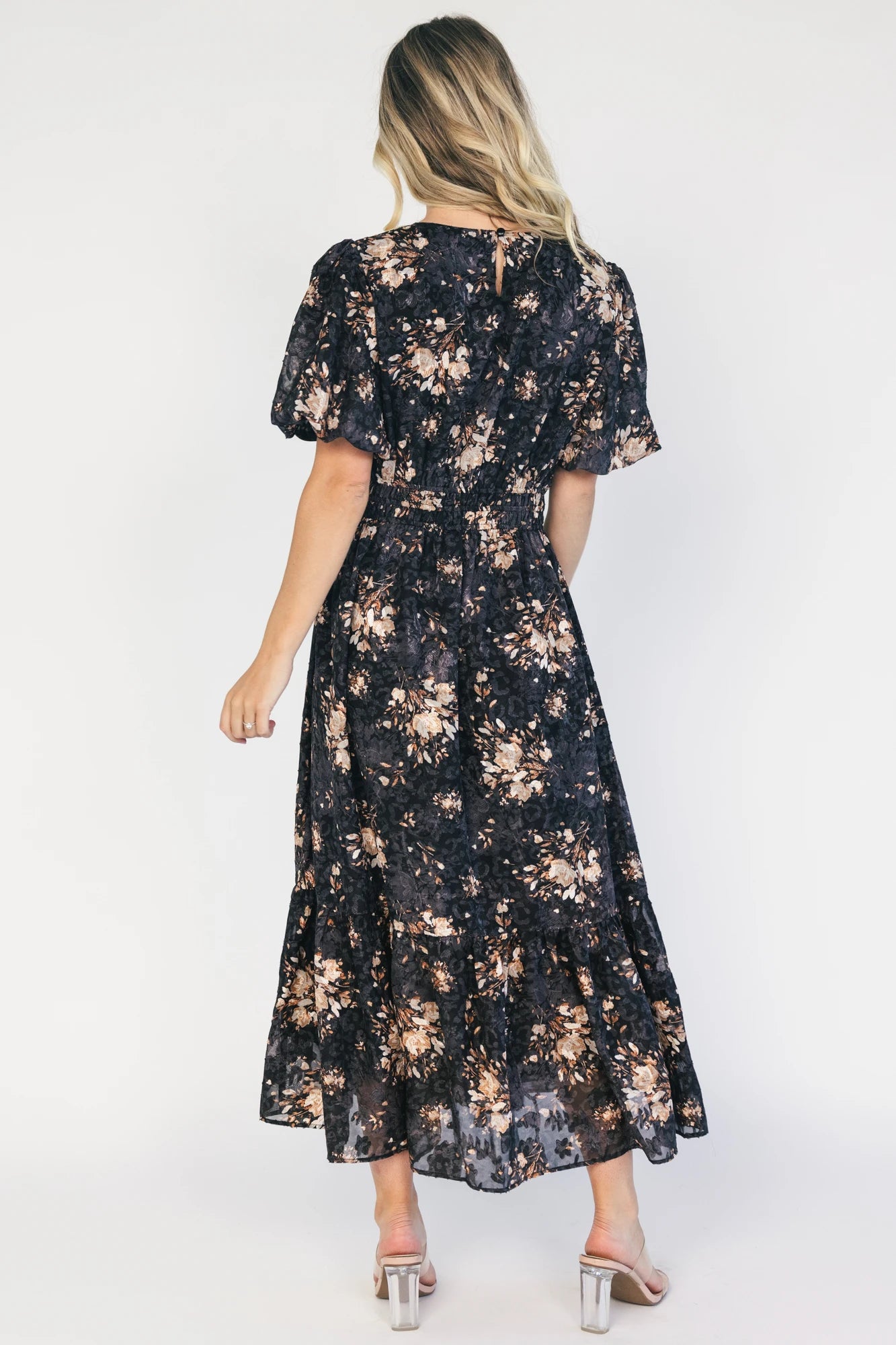 Model wearing a black floral midi dress with a round neckline, puff sleeves, and a smocked waist.