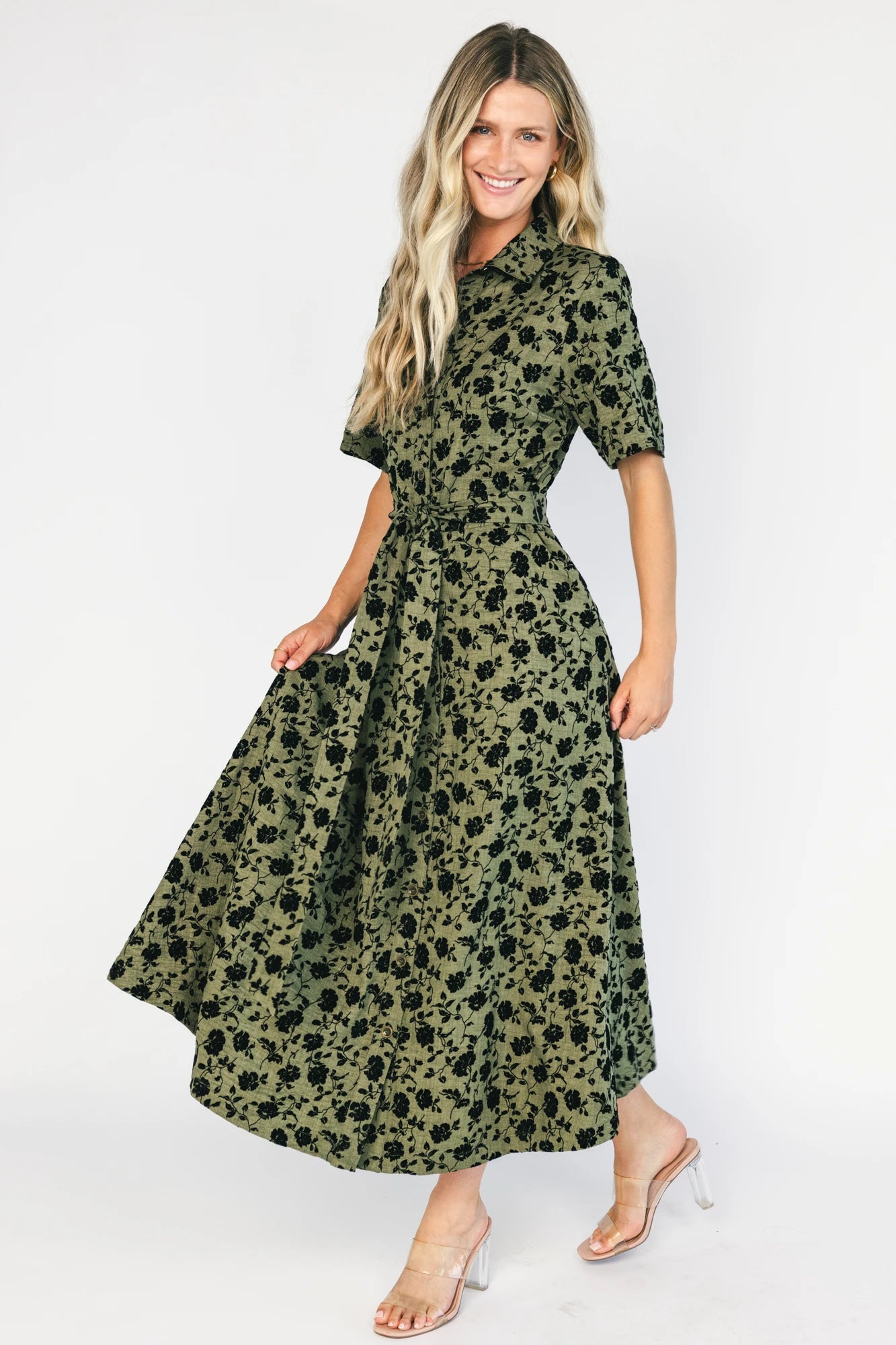 Deep olive floral midi shirt dress with a collared neckline, button-front closure, short sleeves, removable waist tie, side pockets, and fit-and-flare skirt.