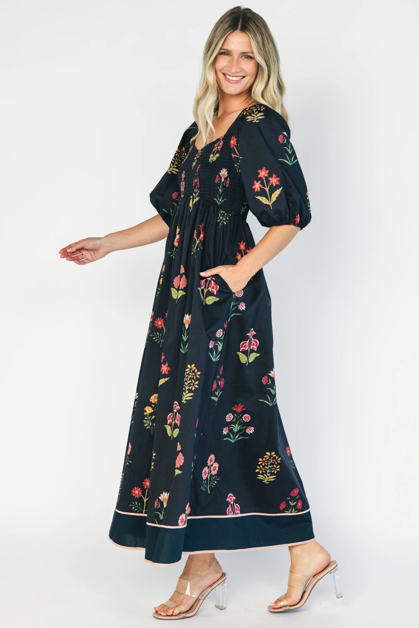 Navy floral maxi dress with a V-neckline, short puff sleeves, empire waist, fit-and-flare skirt, and contrast border hem.