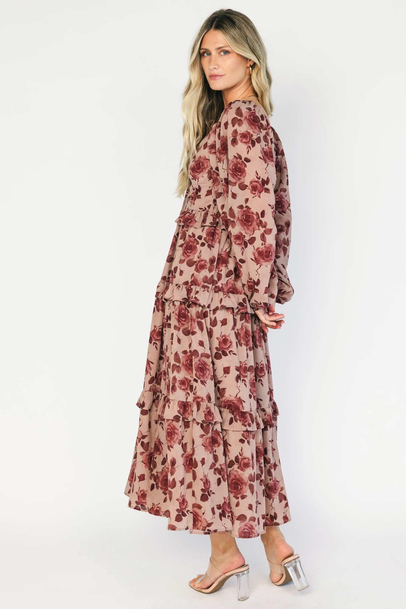 Model wearing a dusty mauve floral maxi dress with a sweetheart neckline, adjustable tie-front bust, and long sheer sleeves.