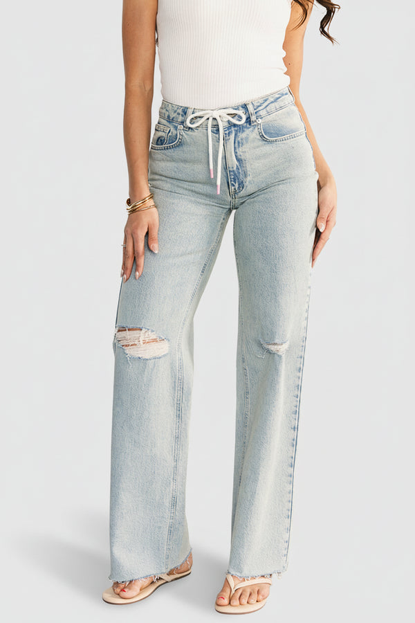 Front view of Ronda mid-rise light wash jeans on model, showing distressed knees, white drawstring waist and raw frayed straight leg hem.
