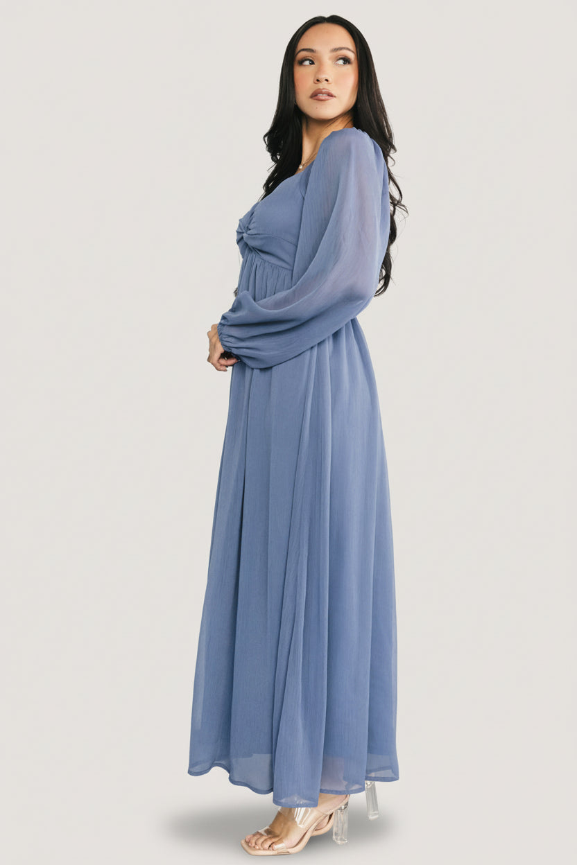 Lifestyle shot of the Dione georgette midi dress in dusty blue, showing sleeve cuff detail and the dress's flattering silhouette.