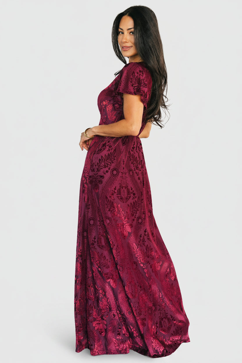 Styled detail shot of V-neck, empire seam, and lining of the Kimberly Velvet Maxi Dress in wine highlighting fabric composition.