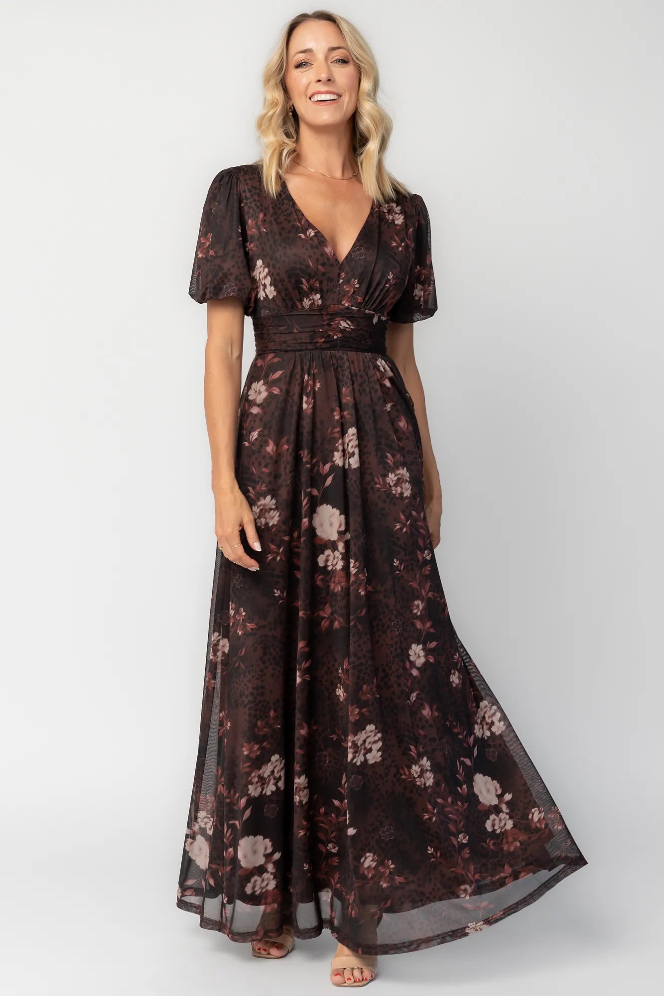 Model wearing a clove floral maxi dress with a deep V-neckline, short sleeves, and an empire waist.