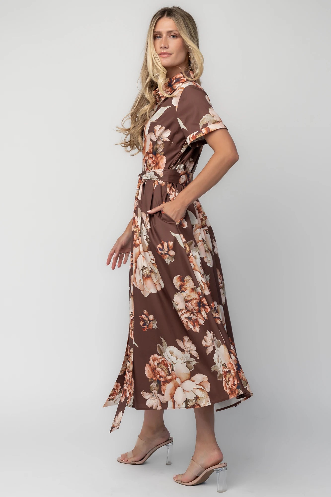 Model wearing the Blythe Midi Dress in Brown Floral featuring a collared neckline, functional button-front bodice, short rolled sleeves, and a removable waist tie.