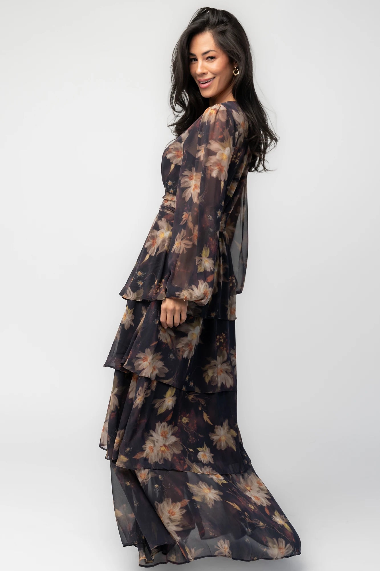 Model wearing the Mariella Tiered Maxi Dress featuring a V-neckline, long sheer puff sleeves, a smocked back waist, and a flowing tiered chiffon maxi skirt with a romantic floral print.