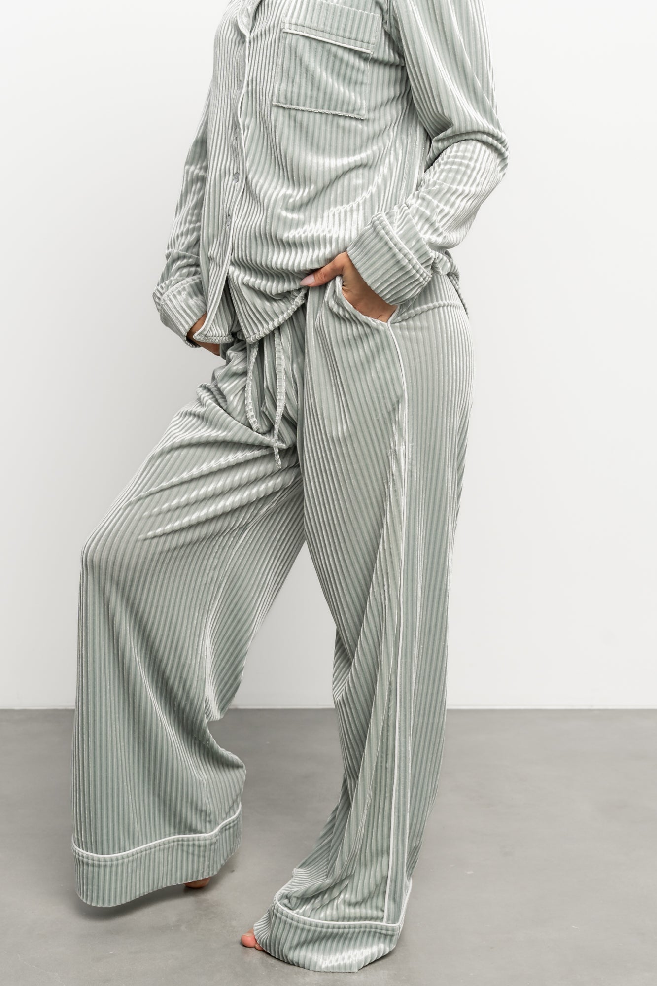 Close-up of ribbed velvet fabric texture in light sage, highlighting soft stretch and subtle vertical rib pattern.