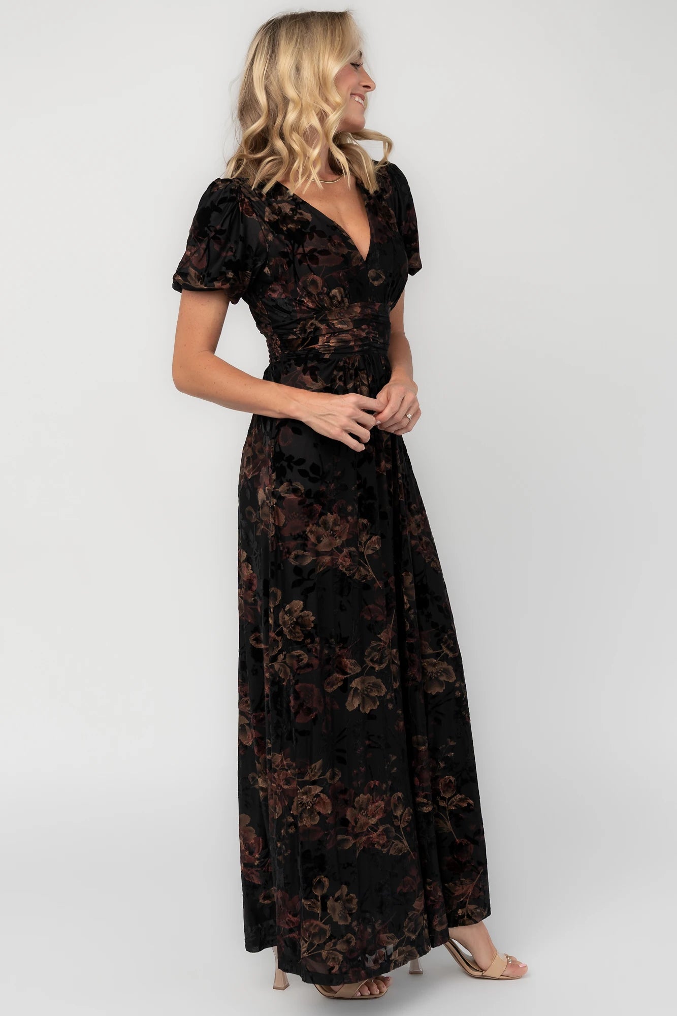 Black embossed velvet floral maxi dress with a V-neckline, short puff sleeves, gathered waist, side pockets, and a flowing full-length skirt.