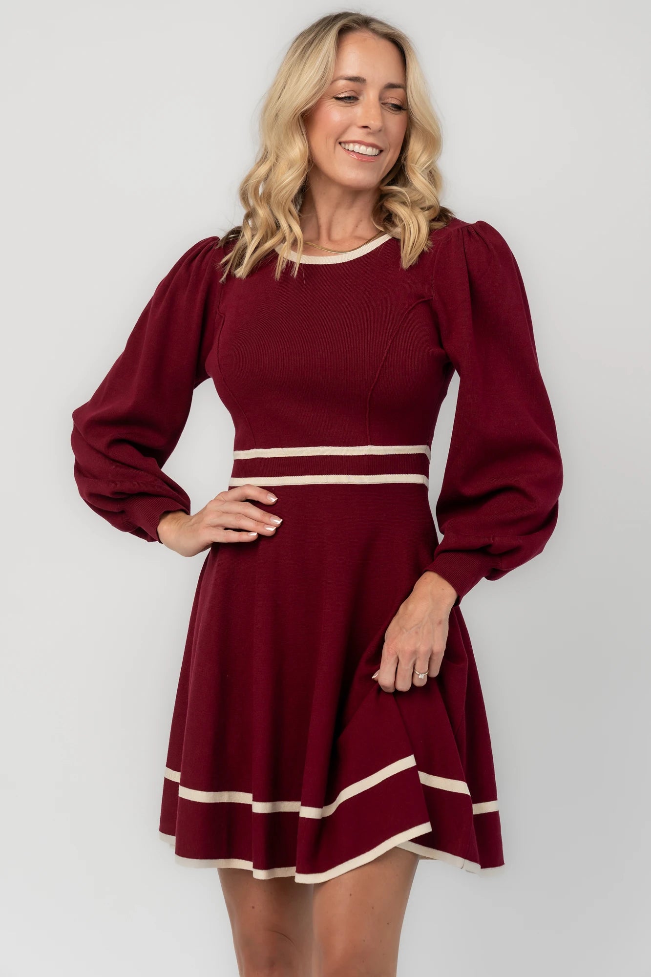 Rich wine knit mini dress with cream contrast trim, long balloon sleeves, a fitted waist, and a flared skirt.