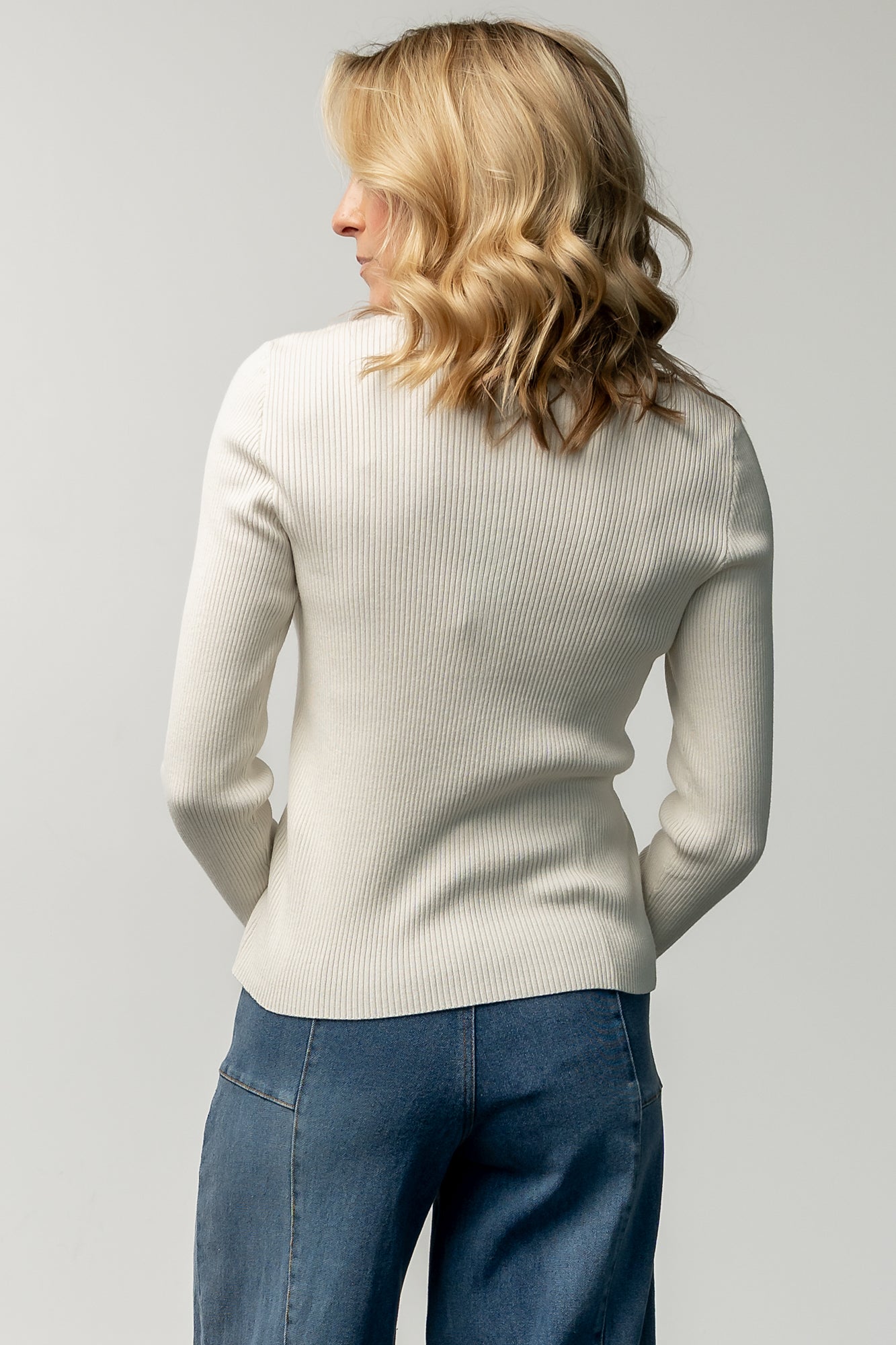 Styled outfit shot: model wearing the Leo ivory henley paired with high-rise wide-leg jeans and a long coat, showing versatile everyday styling.