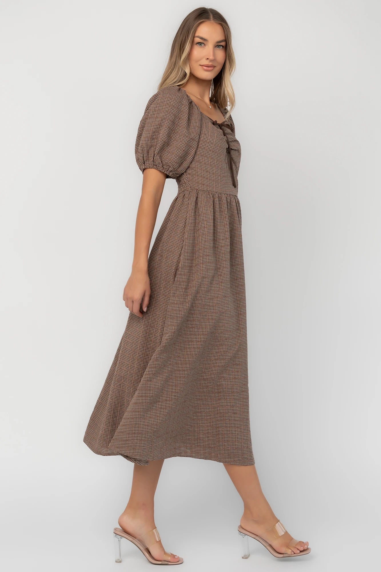 Mocha gingham midi dress with a square neckline, puff sleeves, smocked back, side pockets, and a flowing tiered skirt.
