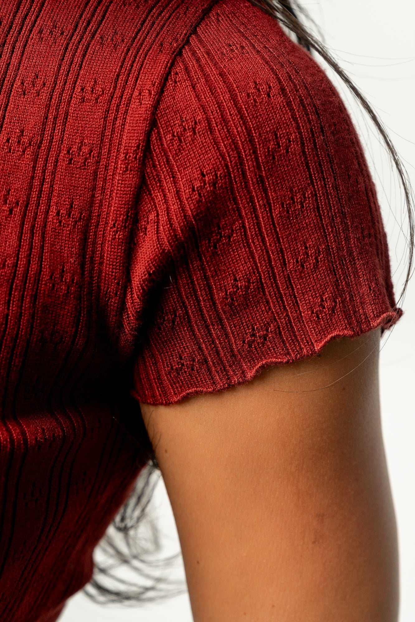Three-quarter view of the Penny Pointelle top in brick on model, highlighting short sleeves, scalloped sleeve cuffs, and fitted silhouette.