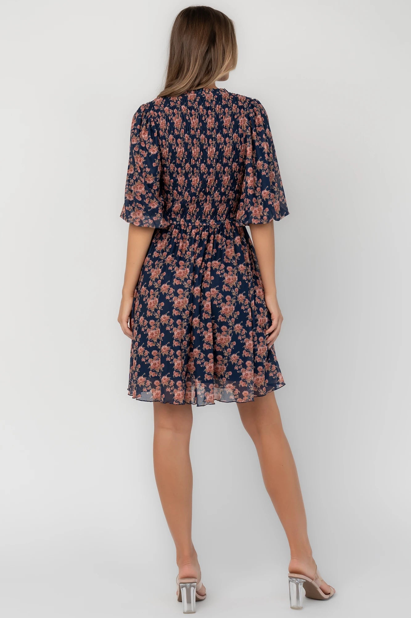 Navy floral mesh mini dress with a round neckline, elbow-length sleeves, smocked bodice, side pockets, and a flowy skirt.