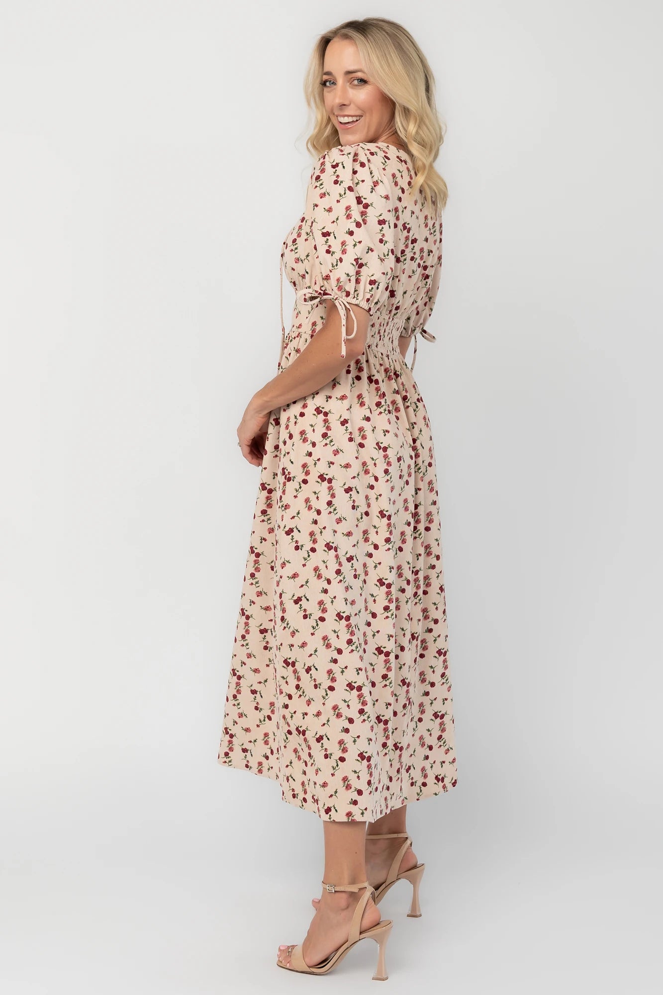 Ivory floral textured midi dress with a split V-neckline, short puff sleeves, empire waist, smocked back, side pockets, and a flowing skirt.