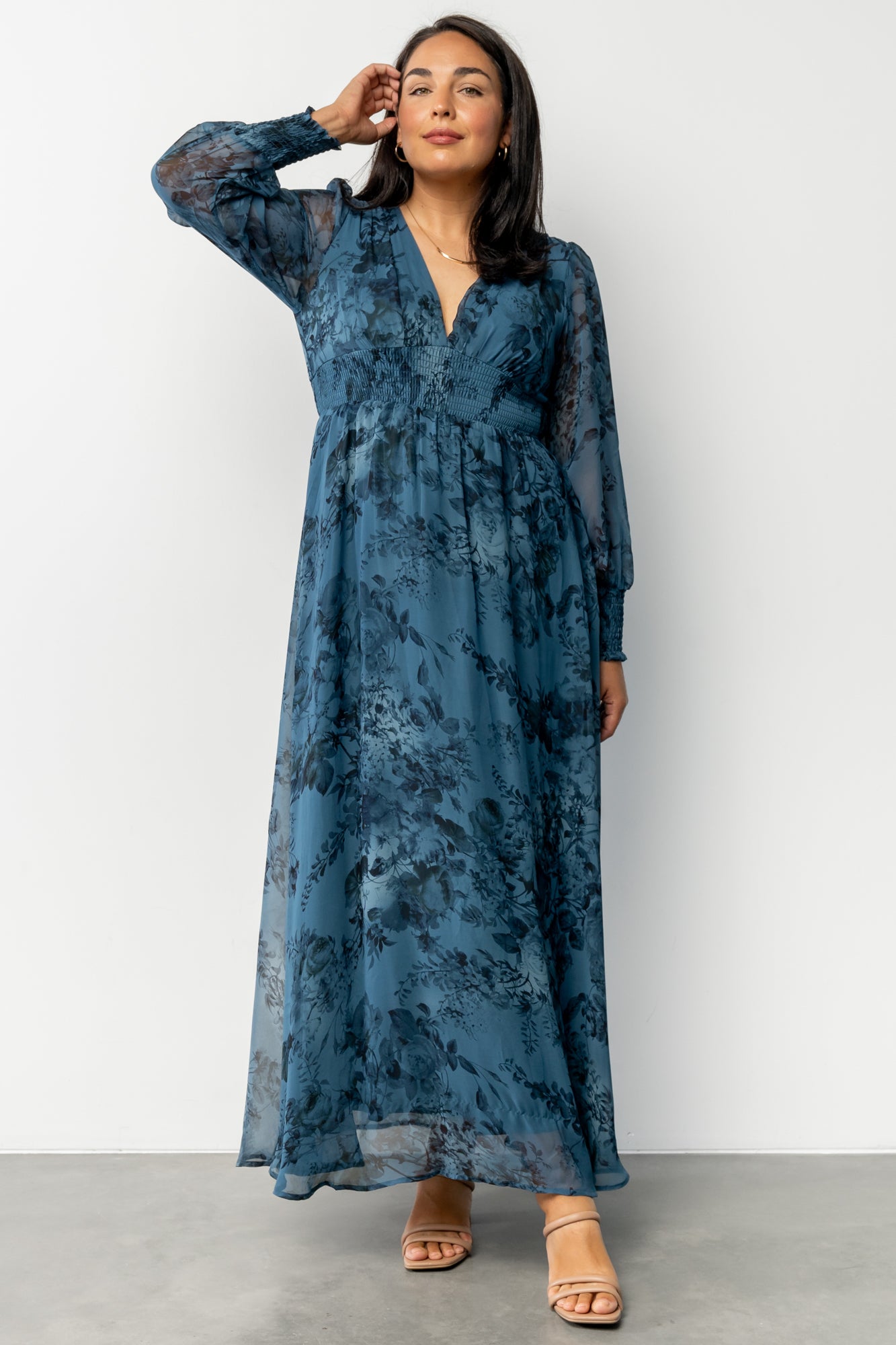 Close-up of deep blue floral chiffon fabric and smocked cuff detail on long sleeve, showing texture and print.
