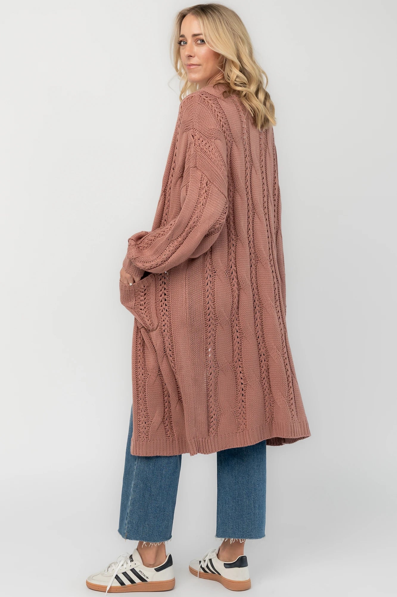 Dusty rosewood cable knit cardigan with an open front, long balloon sleeves, front patch pockets, and a relaxed longline silhouette.
