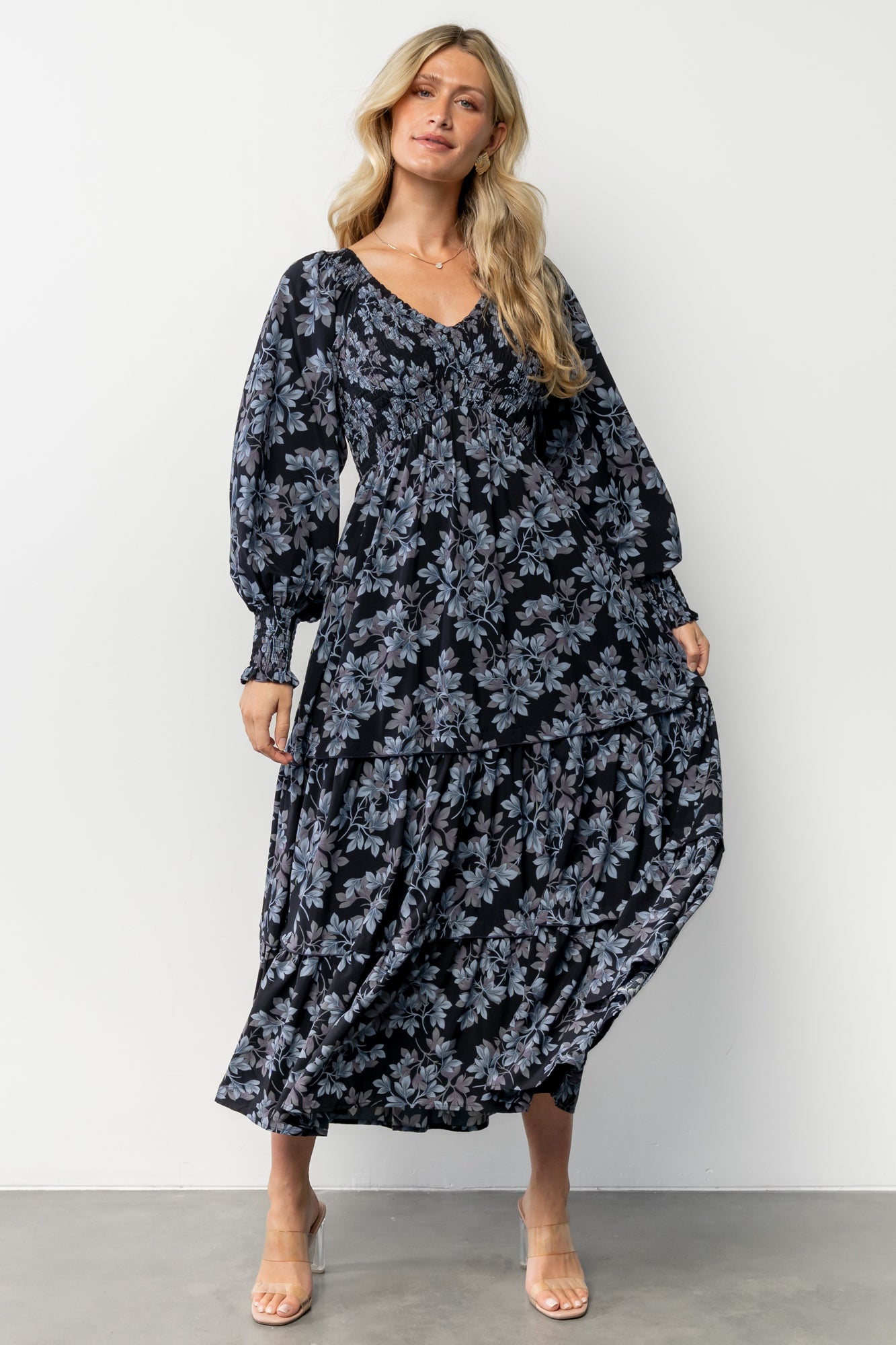 Three-quarter angle of Rayna Smocked Dress showing smocked bodice, long sleeves with smocked cuffs, and soft fabric drape.