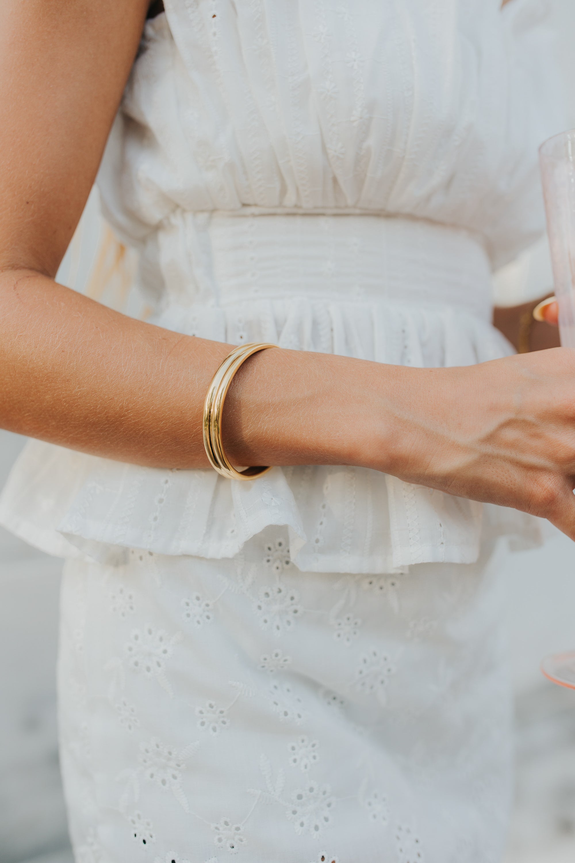 Wrist shot of the open cuff worn stacked with thin bracelets to demonstrate scale, fit, and layered styling.