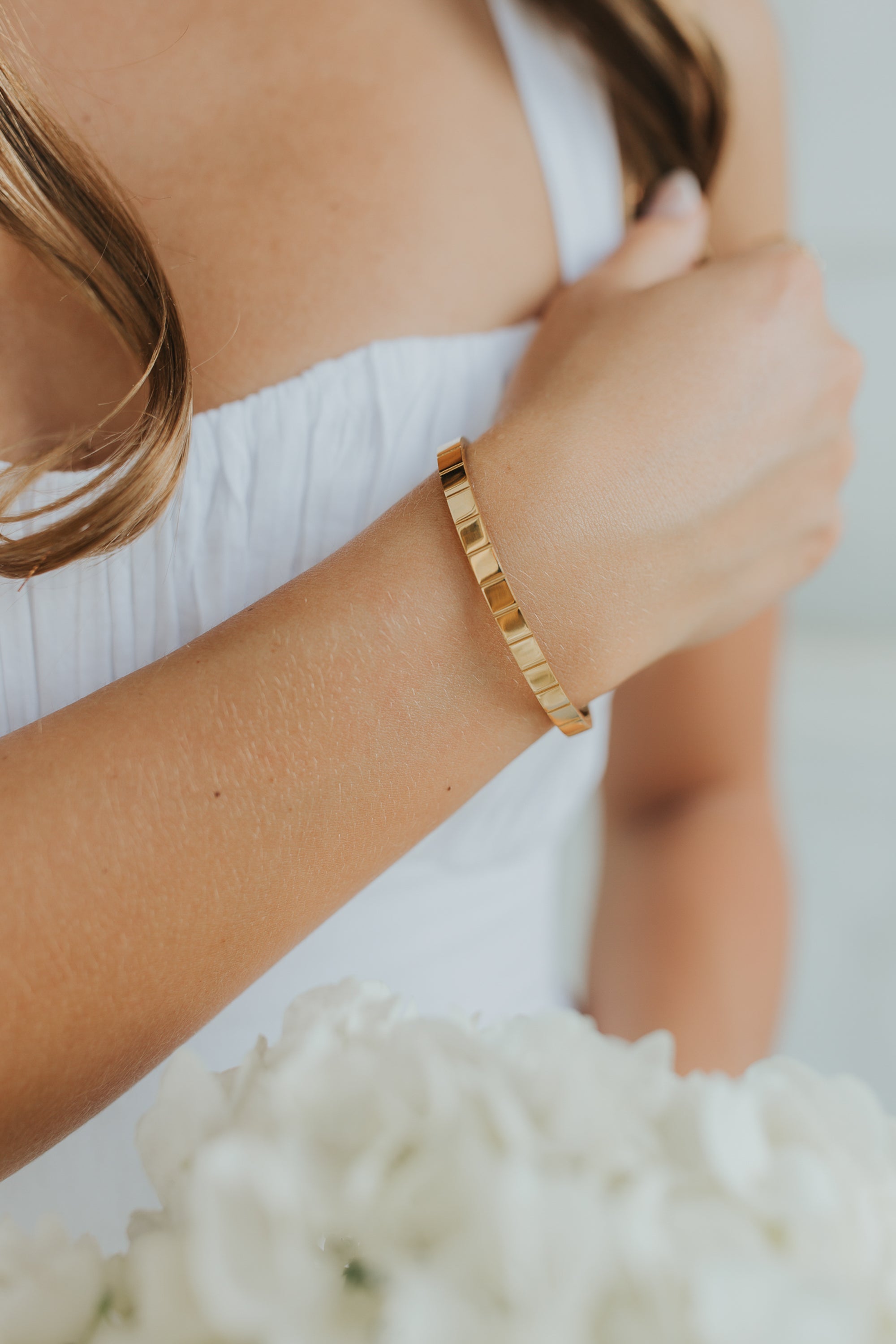 Close-up of the Lily Bracelet in 18K gold-plated finish, showing high-gloss surface and soft beveled edge against a neutral backdrop.