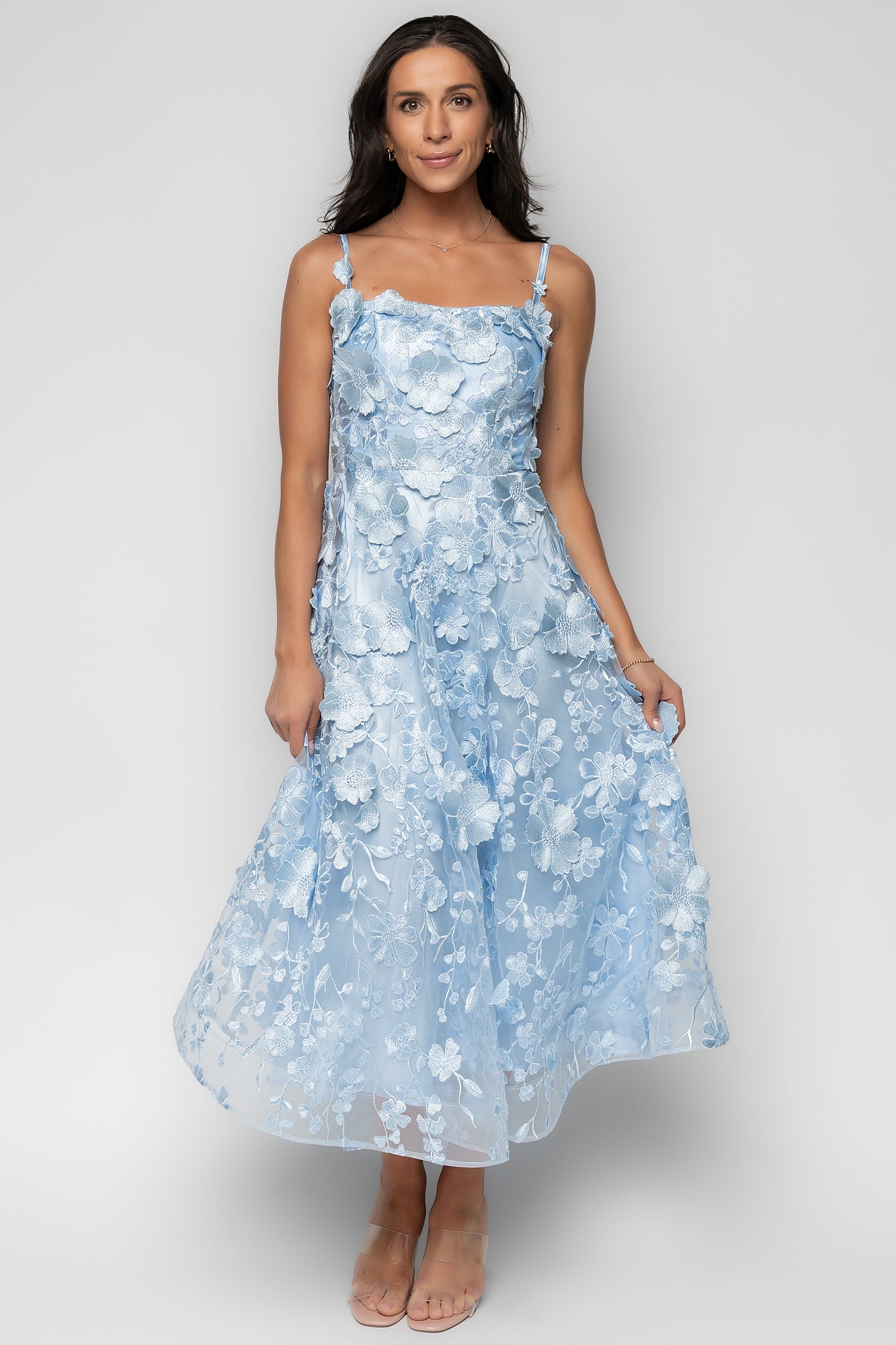 Fabric close-up showing mesh texture and layered appliqué florals with subtle sheen and finely stitched edges.