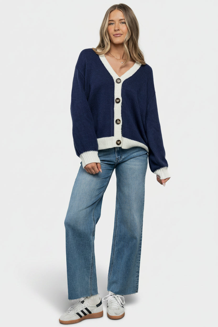 Flat lay of Rory navy cardigan folded to show piping, button placement, and flag back detail.