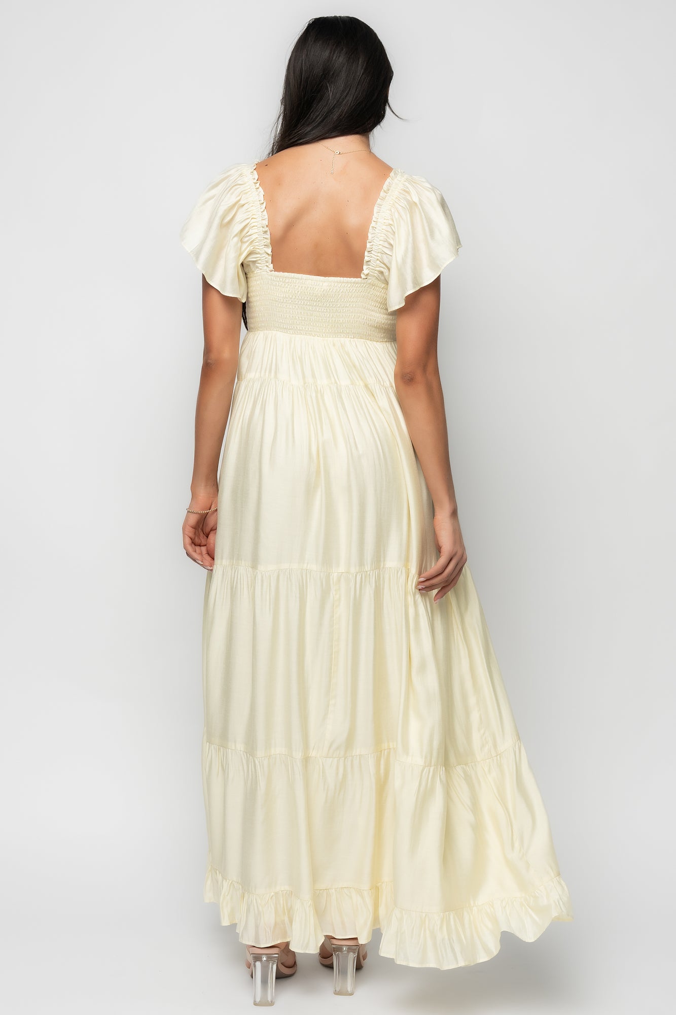 Back view highlighting the smocked back of the Agatha Maxi Dress in pale yellow with relaxed tiers for comfortable fit and movement.