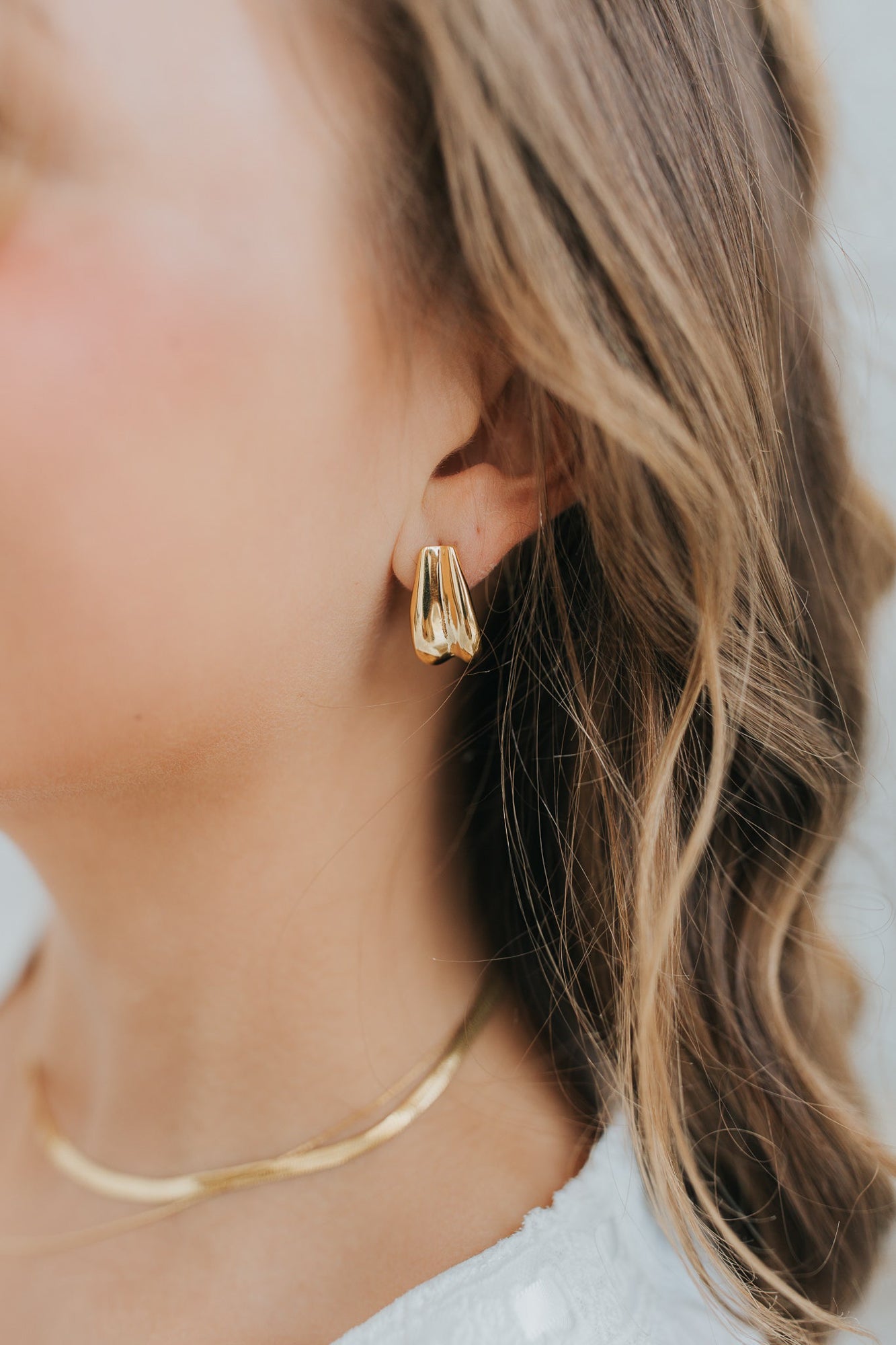 Styled product shot of The Sicily Hoop gold earrings, showing profile of the hoop, the post-back, and the lightweight silhouette.