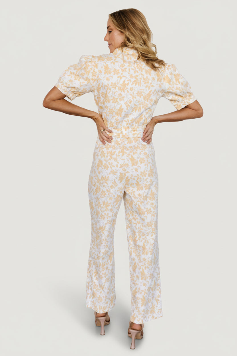 Detail shot of Annalise jumpsuit hem and fabric texture, white background with muted yellow floral print and tailored seams.
