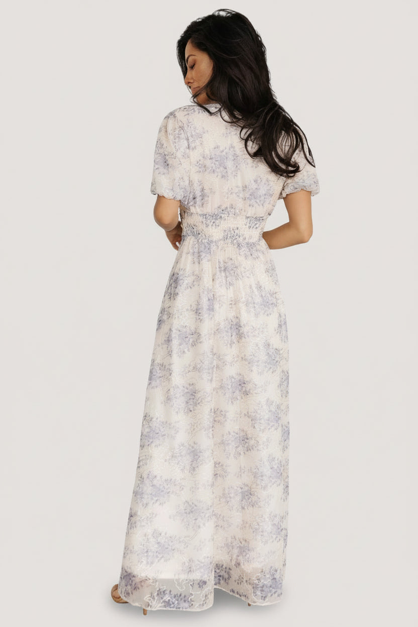 Full-length model shot of cream floral maxi dress walking, highlighting skirt movement and overall silhouette.