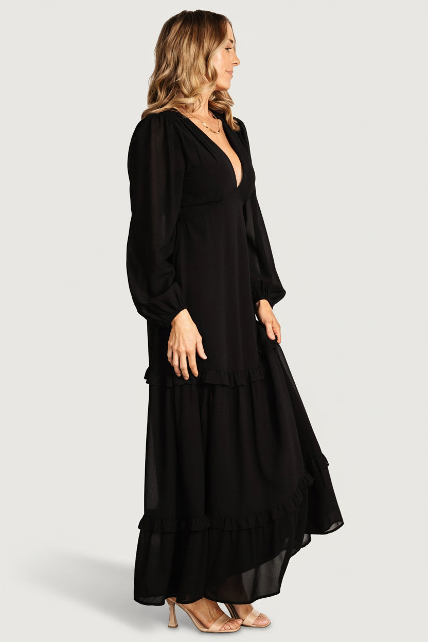 Close-up of the deep V-neck bodice and ruffle tier detail on the black Bowman maxi dress, showing lining and seam finish.