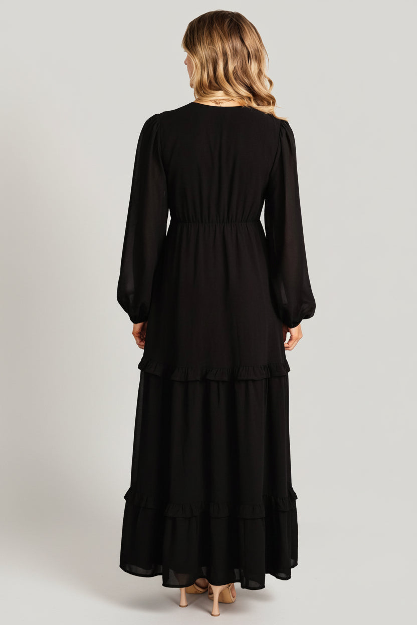 Model wearing the black Bowman Deep V maxi dress with strappy heels to showcase overall silhouette, movement, and sleeve detail.