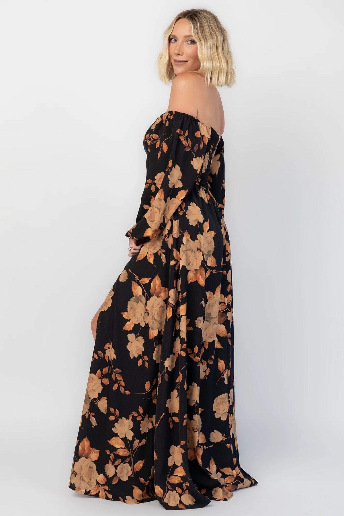 Cordelia Off Shoulder Maxi Dress in Black + Gold Floral with an off-shoulder neckline, billowy sleeves, and a leg slit.