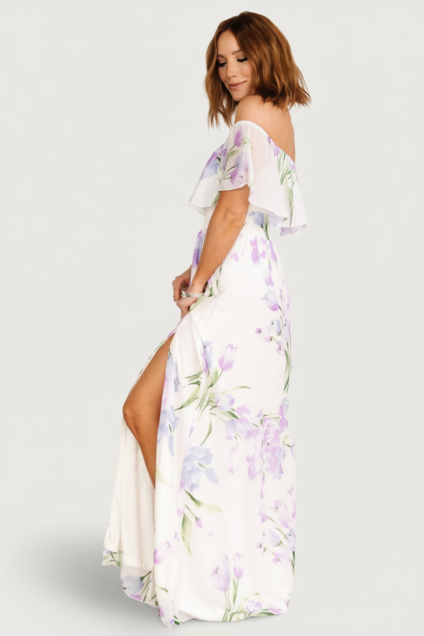 Movement shot of the Daphne maxi dress capturing flowing chiffon skirt, left slit, and soft lavender and purple floral pattern.