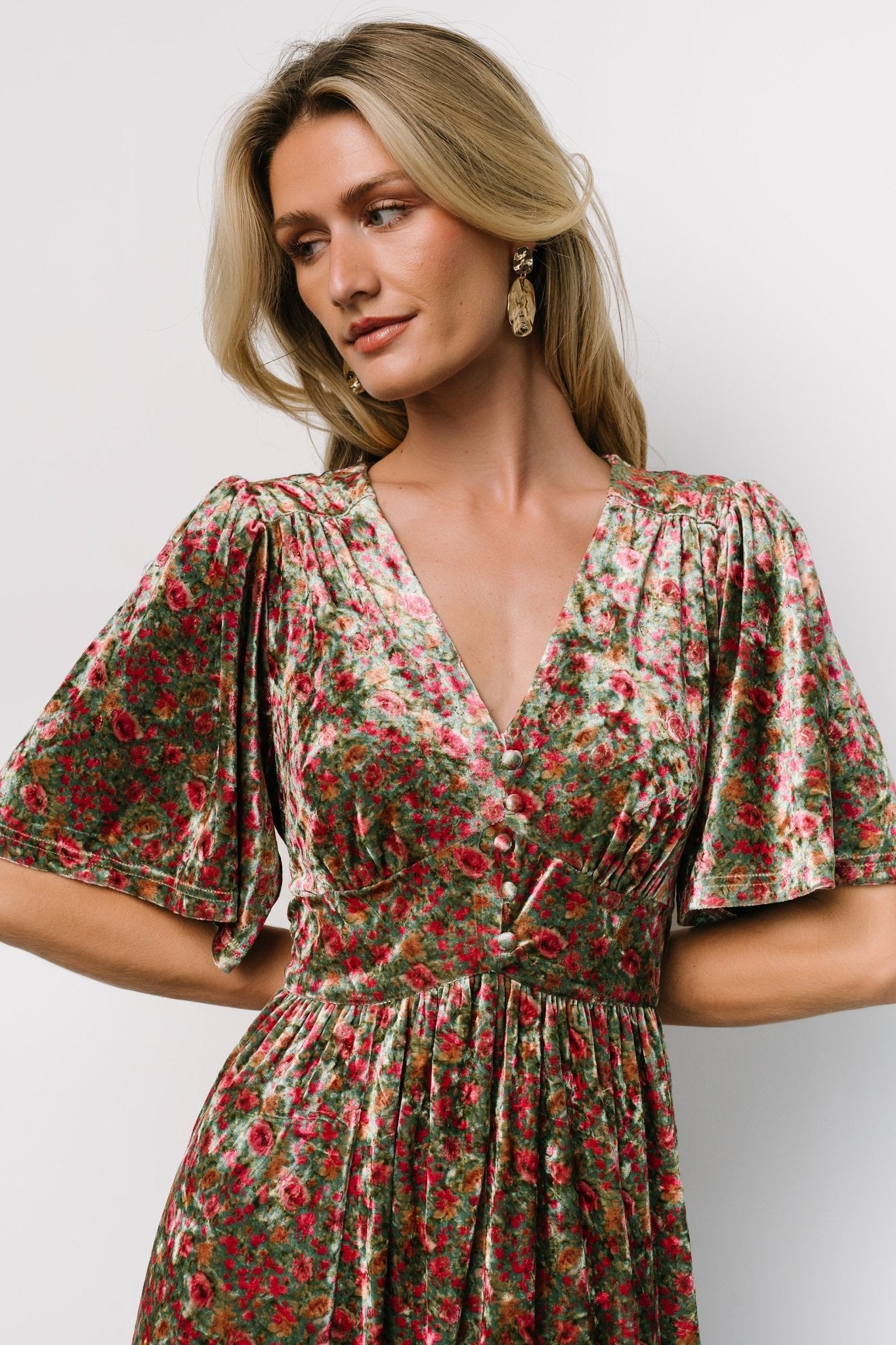 Close-up of bodice detail with faux buttons, gentle gathering at the bust, and subtle gold metallic threads woven into the velvet floral pattern.