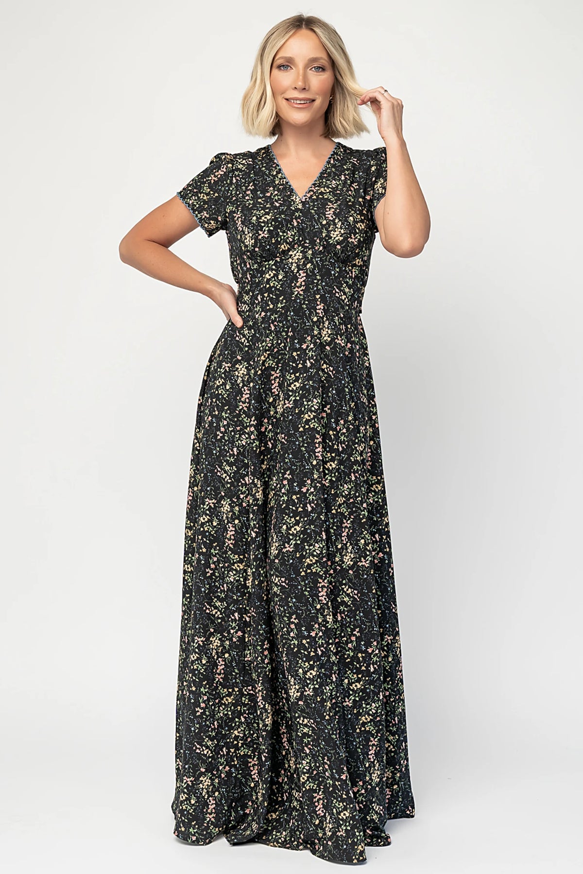 Jada Maxi Dress in Black Floral with V-neckline, blue scalloped trim, flutter sleeves, empire waist, and tie waist.