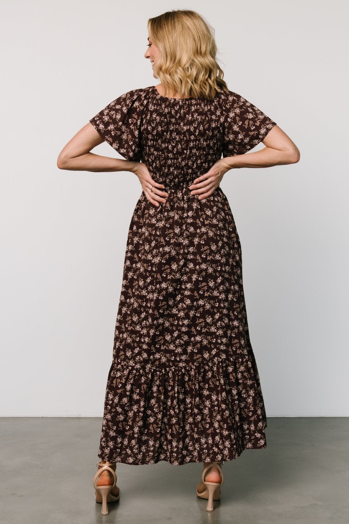 Back view of the clove floral Joanie dress showing the full skirt, back seam detail and overall midi length on model.