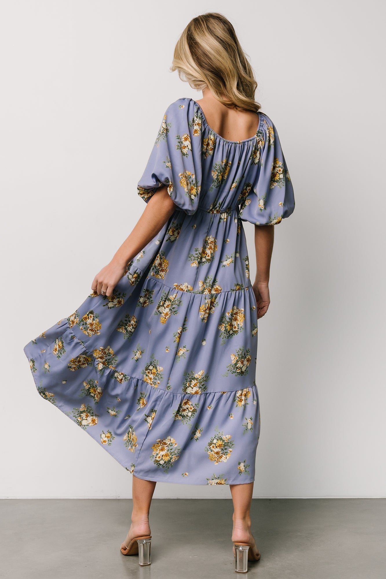 Styled shot of the Judith chiffon midi dress paired with simple accessories, emphasizing blue background that pulls purple and golden florals.