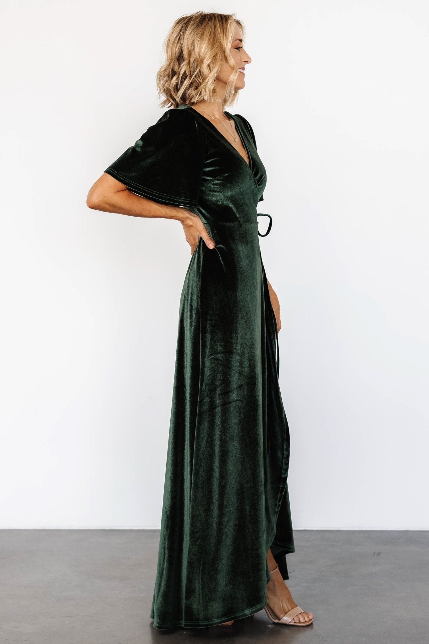 Back view of the deep green velvet maxi wrap dress showing full lining, smooth back seam, and graceful hemline.