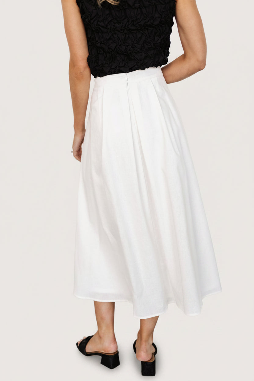 Close-up of the skirt's pleated fabric and waistband showing texture and seam details, illustrating material and construction.