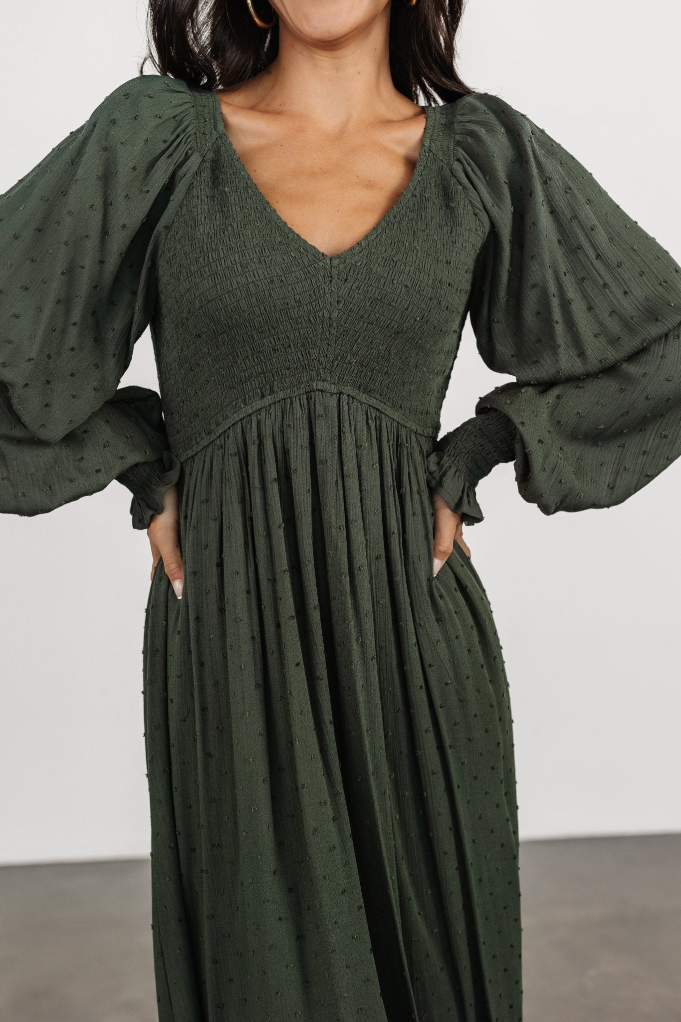 Back view of the Lainey dress in deep olive, showing sleeve length, smocked back bodice, and tiered hem.