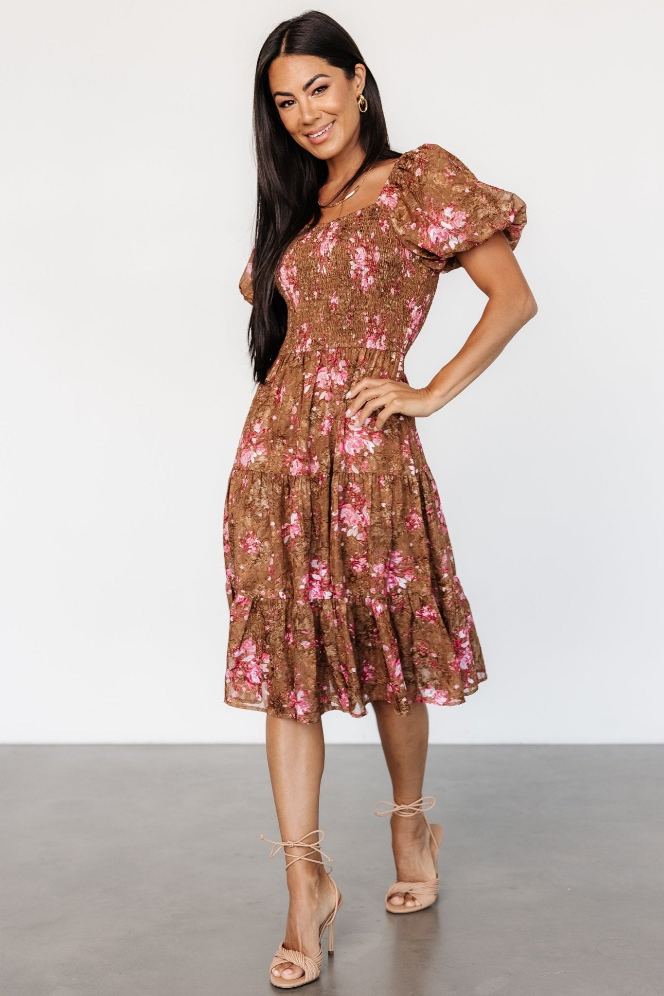 Studio image of Lizzy midi dress on model, showing overall fit, puffed sleeves, and flowing tiered chiffon skirt in copper and pink.
